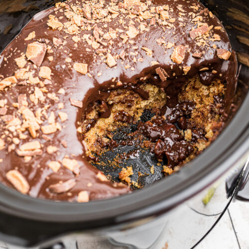 scoop taken out of butterfinger cake in slow cooker.