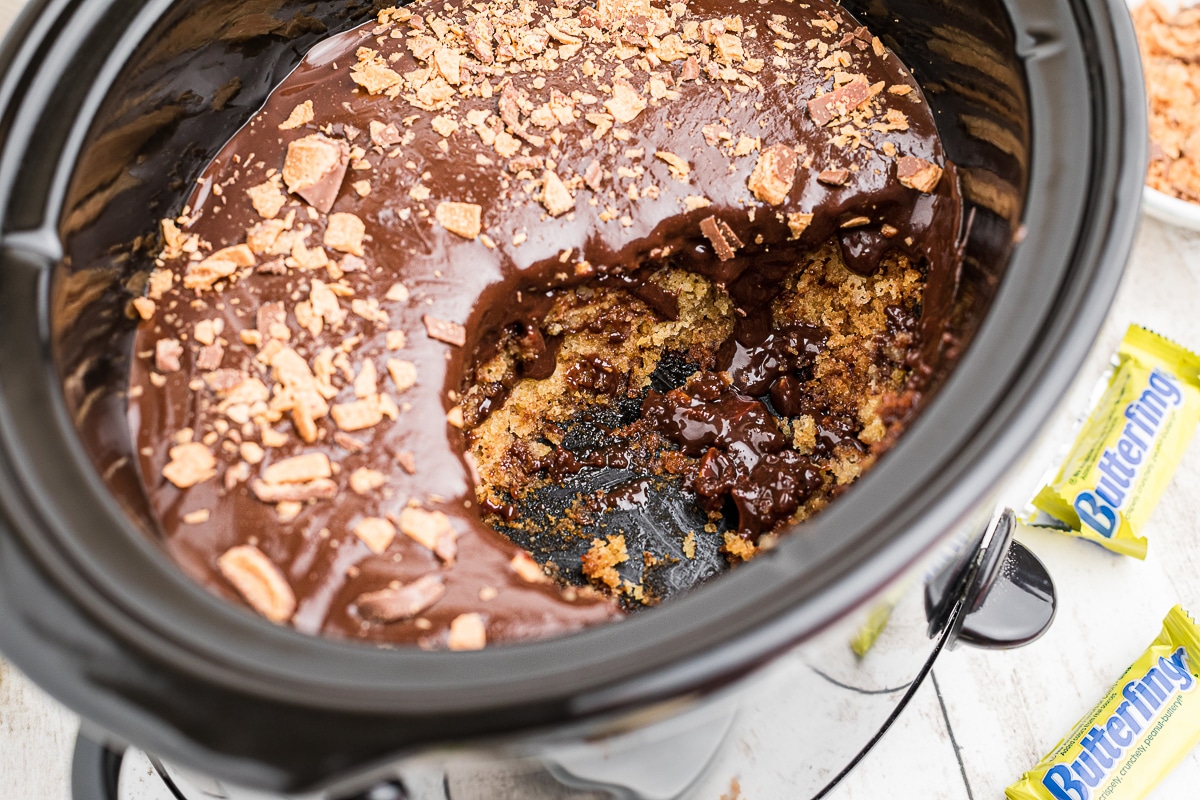 scoop taken out of butterfinger cake in slow cooker.