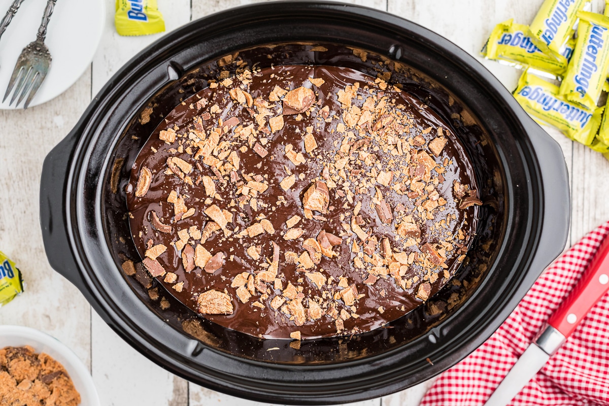 overhead shot of butterfinger cake with hot fudge topping in crockpot.