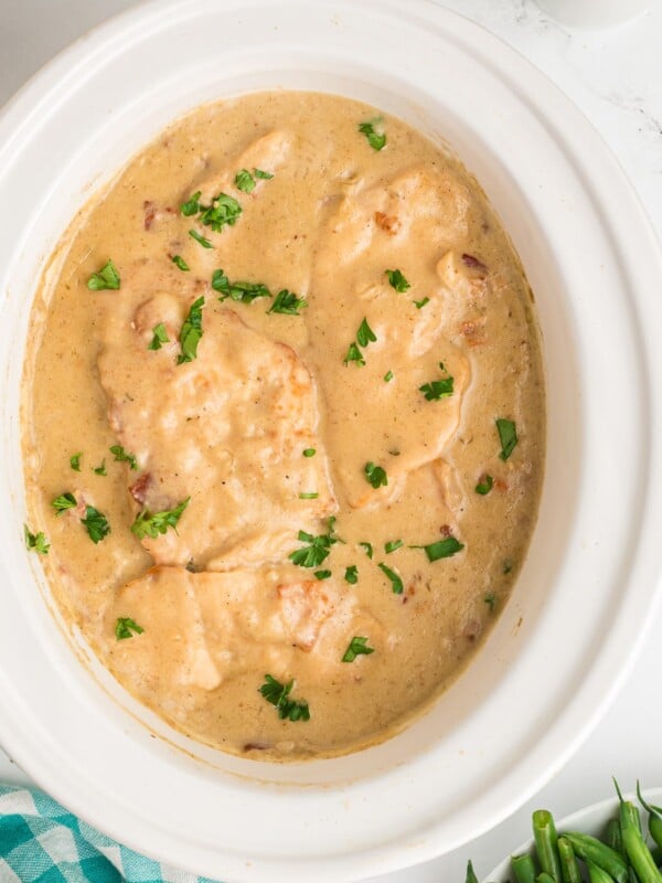 smothered chicken in slow cooker cooker with parsley on top.