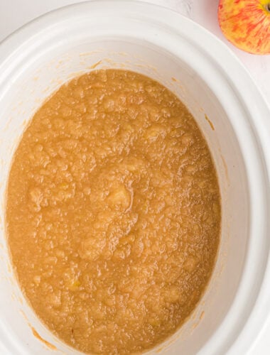 close up of applesauce cooked in a white slow cooker.