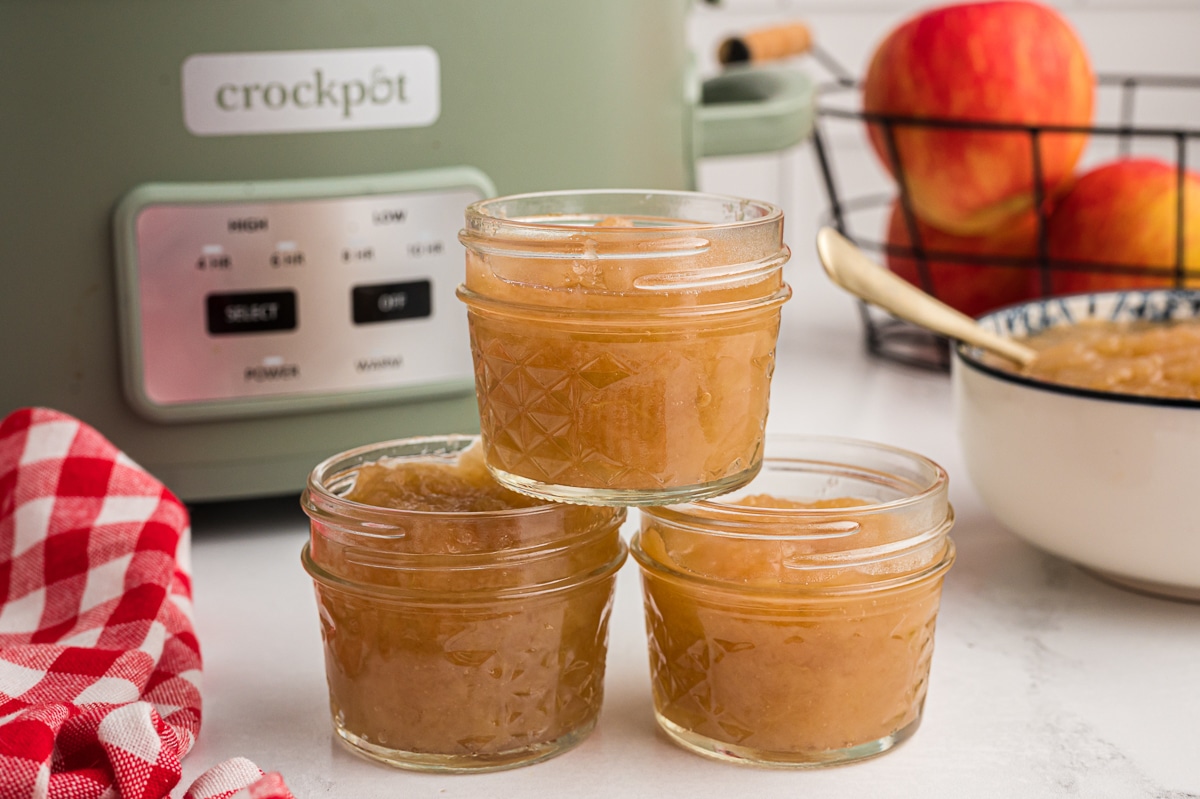 3 jars of applesauce in front of crockpot.