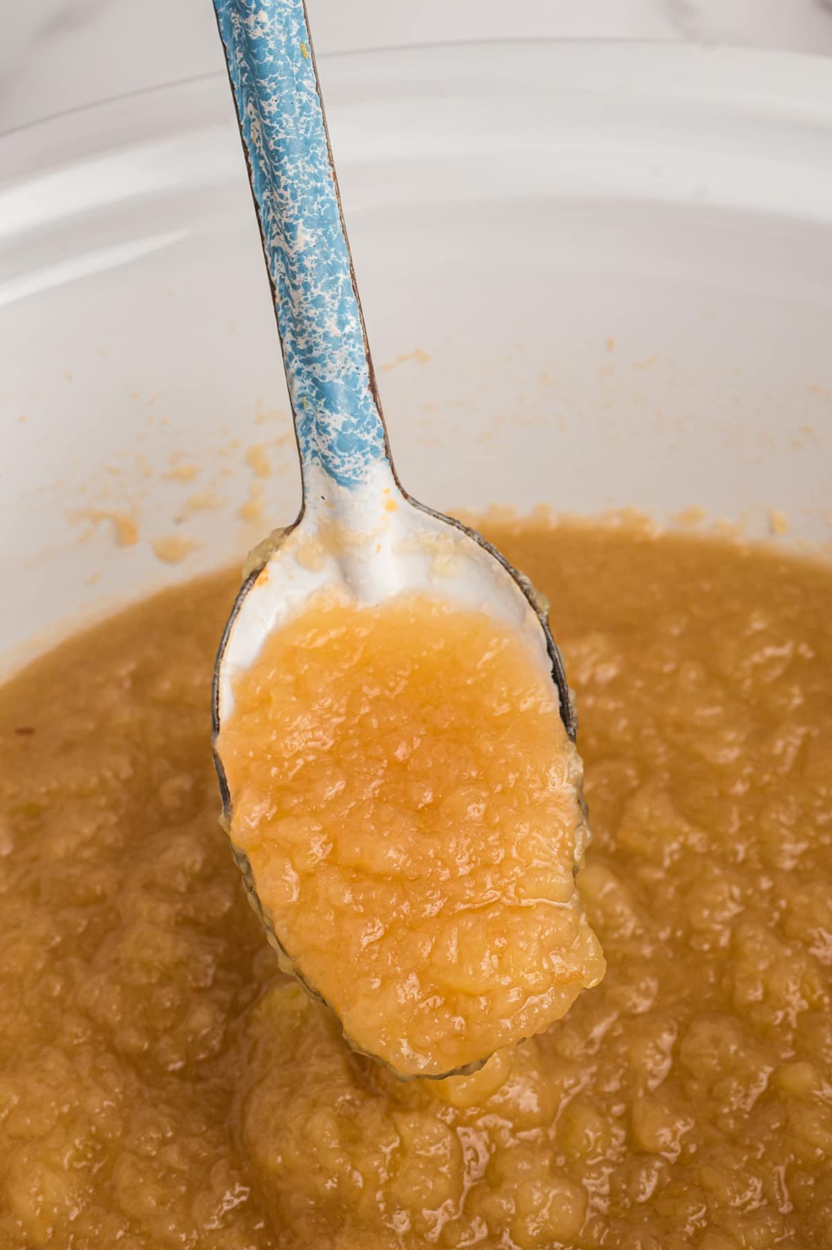 applesauce on a spoon in slow cooker.
