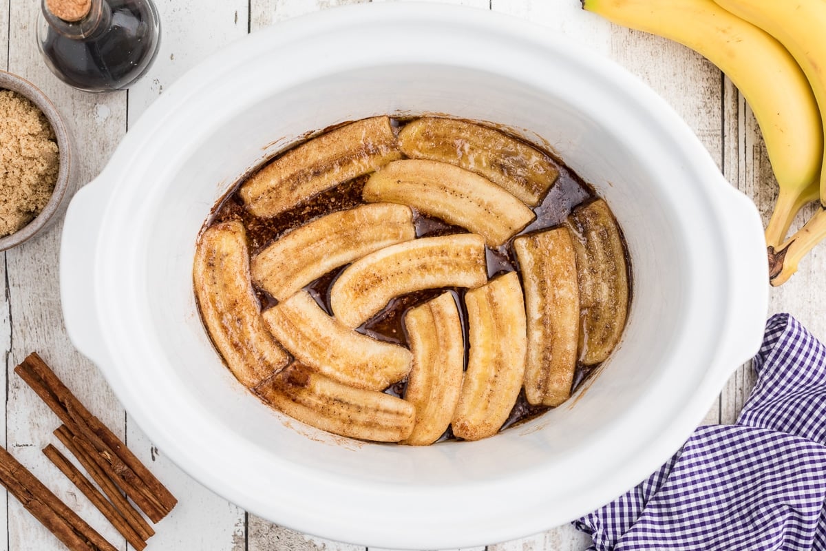 Overhead shot of bananas foster in white crockpot.