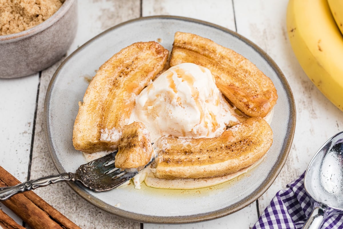 fork cutting into bananas foster with ice cream.