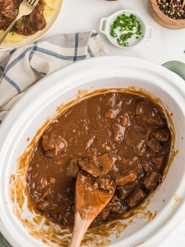 beef tips and gravy in slow cooker with spoon in it.