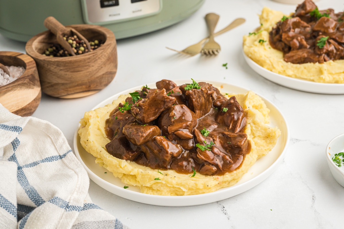 beef tips on plate over mashed potatoes.