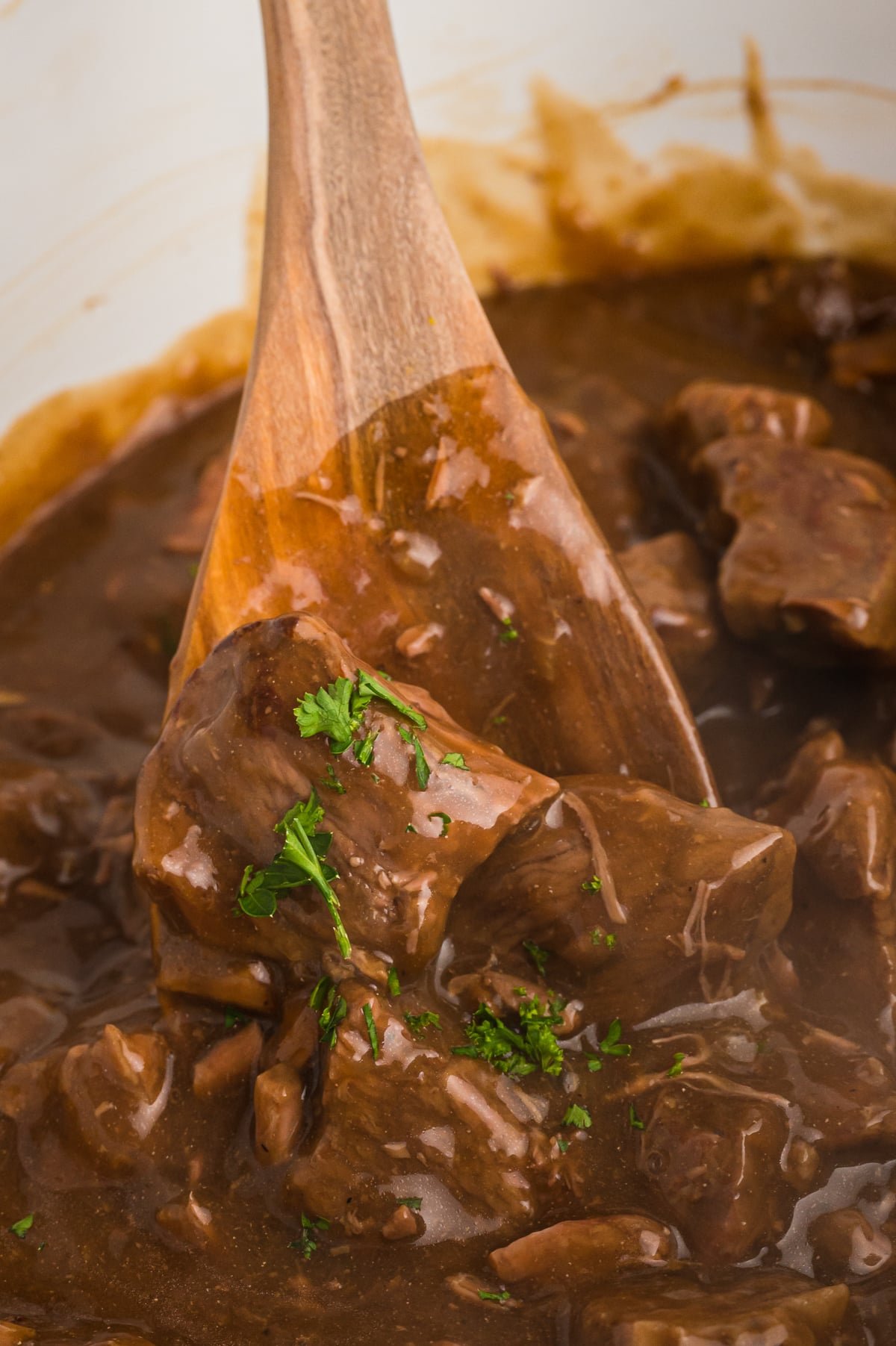 close up of beef tips on a wooden spoon.