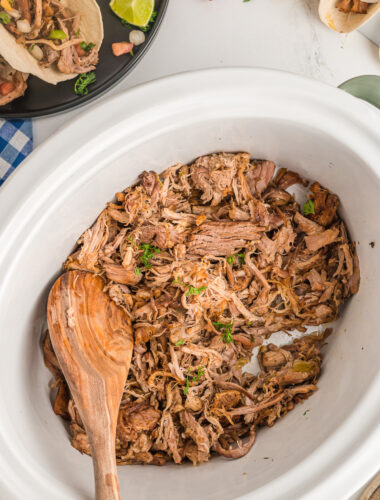 carnitas in slow cooker with tacos on the side.