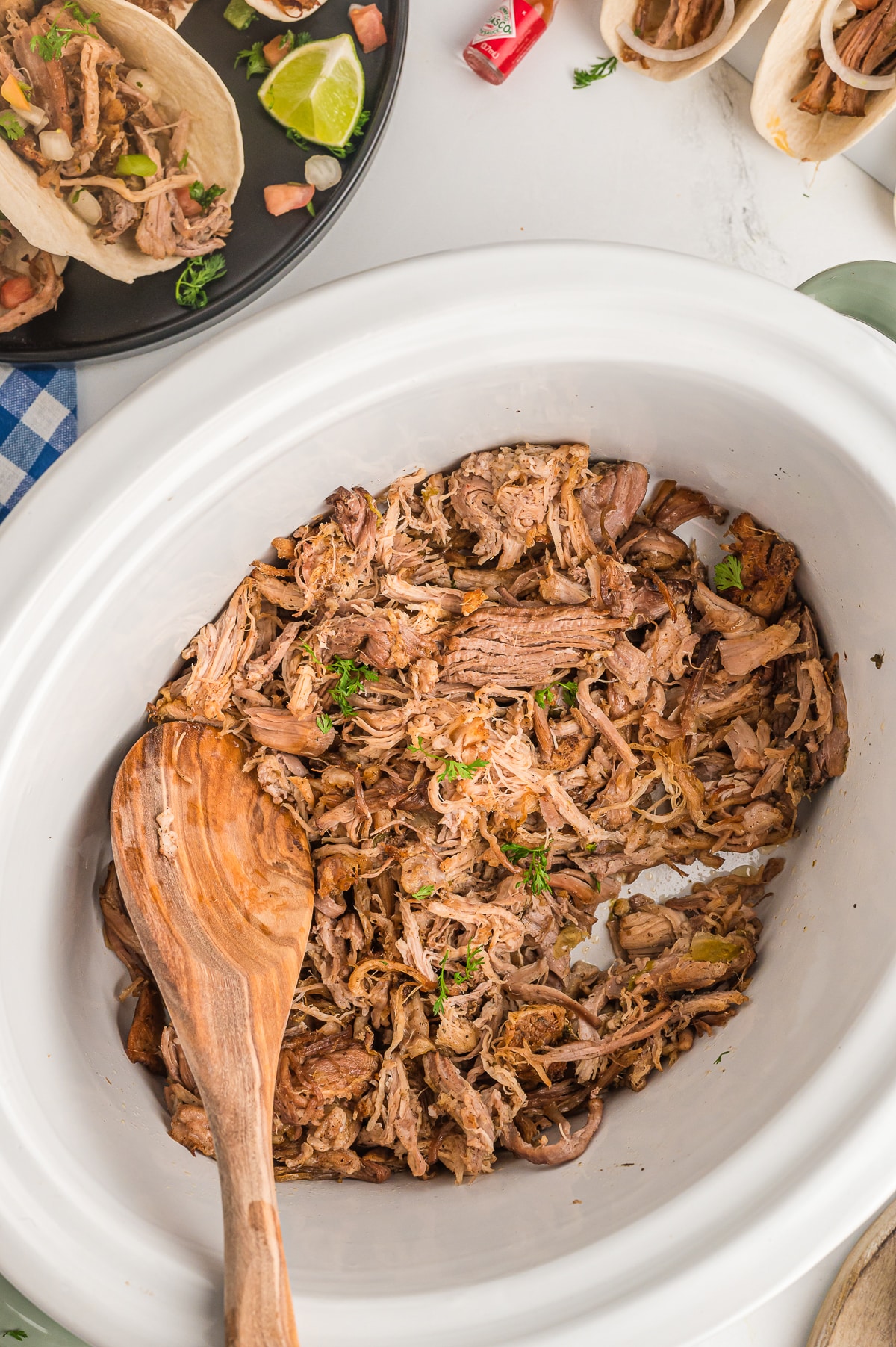 carnitas in slow cooker with tacos on the side.