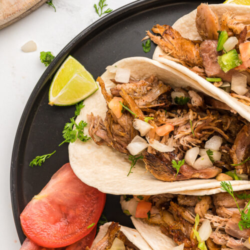 close up of carnitas tacos on a plate.