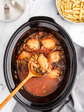 chicken cacciatore cooked in slow cooker with wooden spoon.
