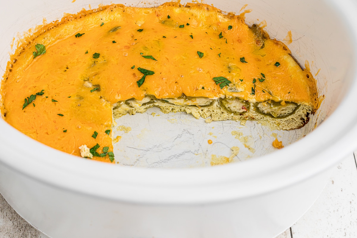 chile relleno casserole with chunk out of it in slow cooker.