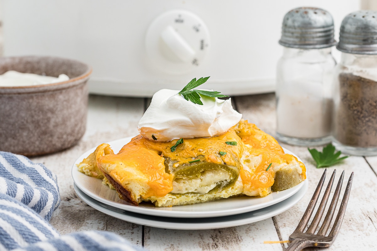 chile relleno casserole slice on plate with sour cream.