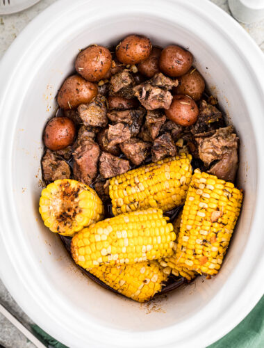 crockpot full of steak potatoes and corn.