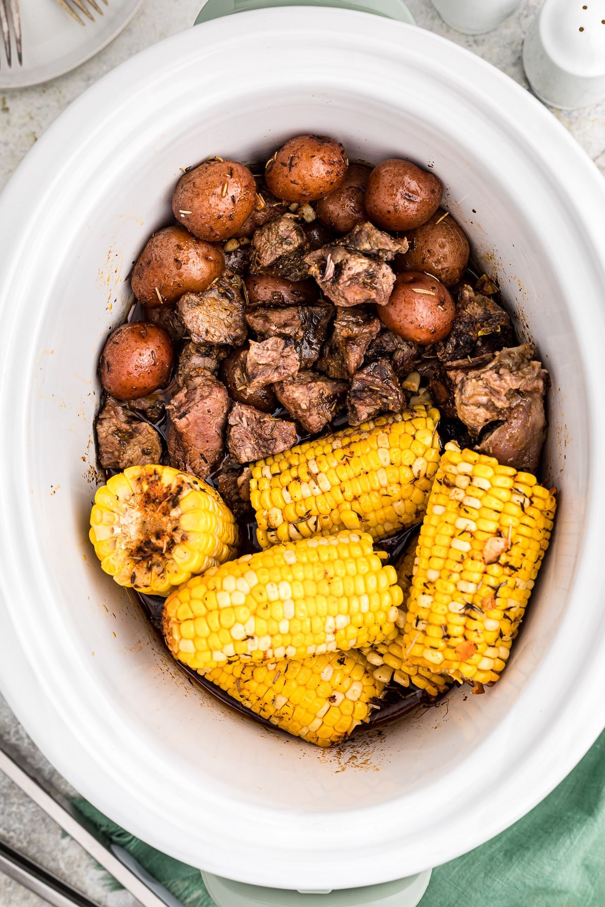 crockpot full of steak potatoes and corn.