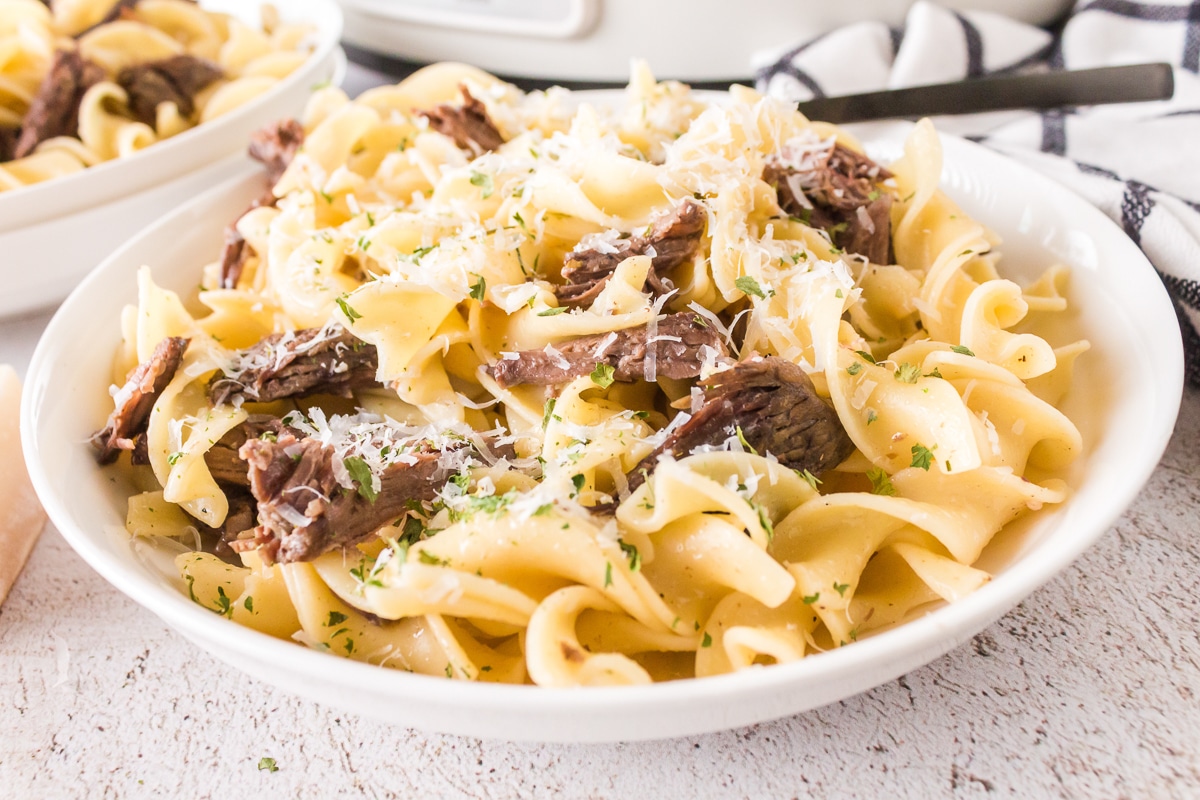 plate of beef and noodles with parmesan on top.