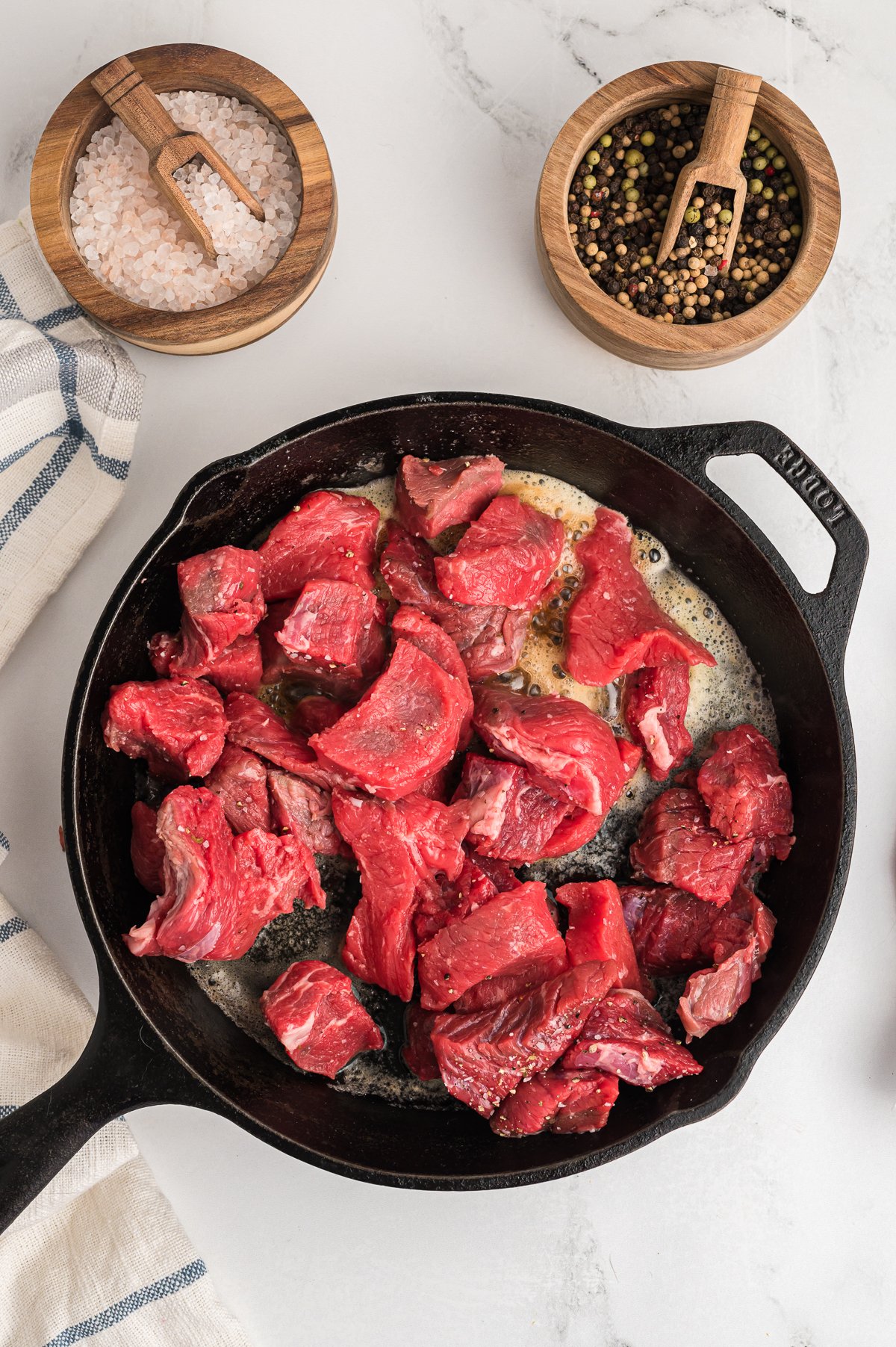 uncooked beef tips in a skillet, browning.