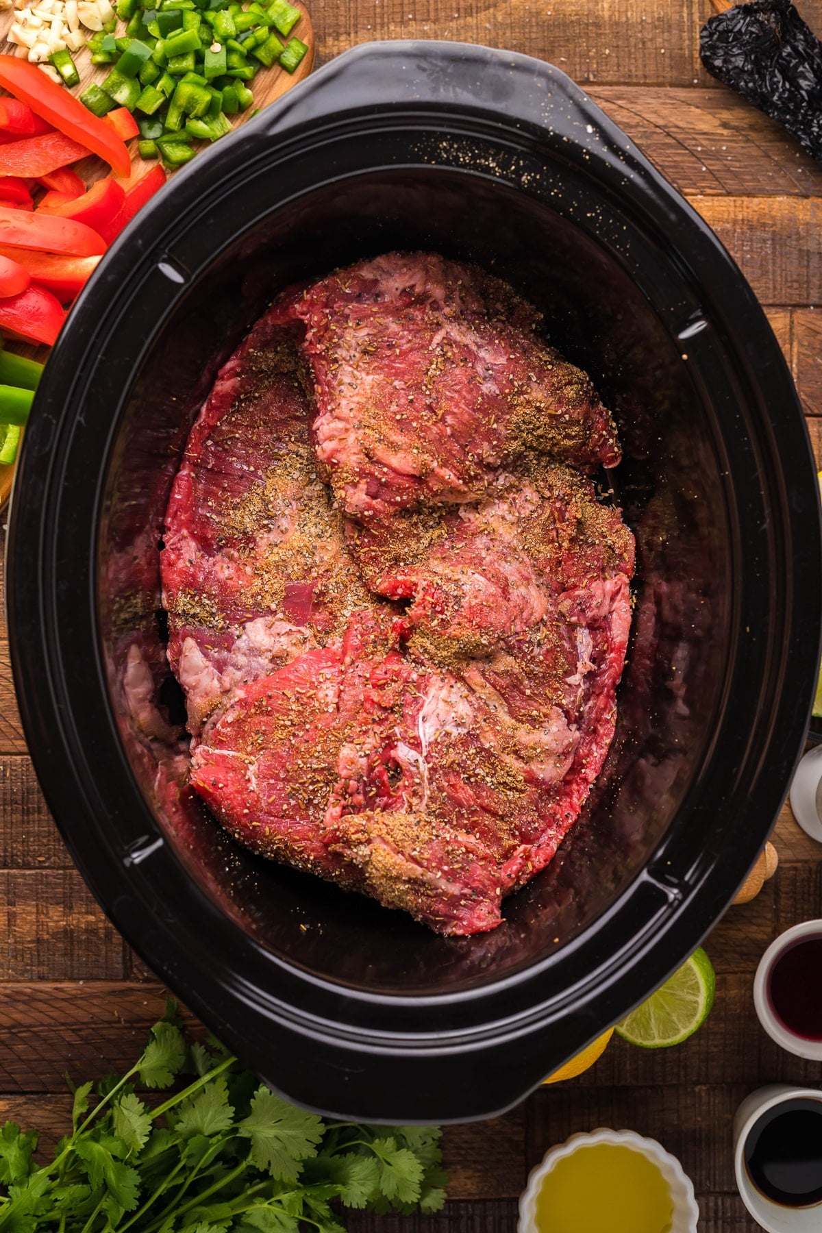 skirt steak with seasonings on top in a crockpot.