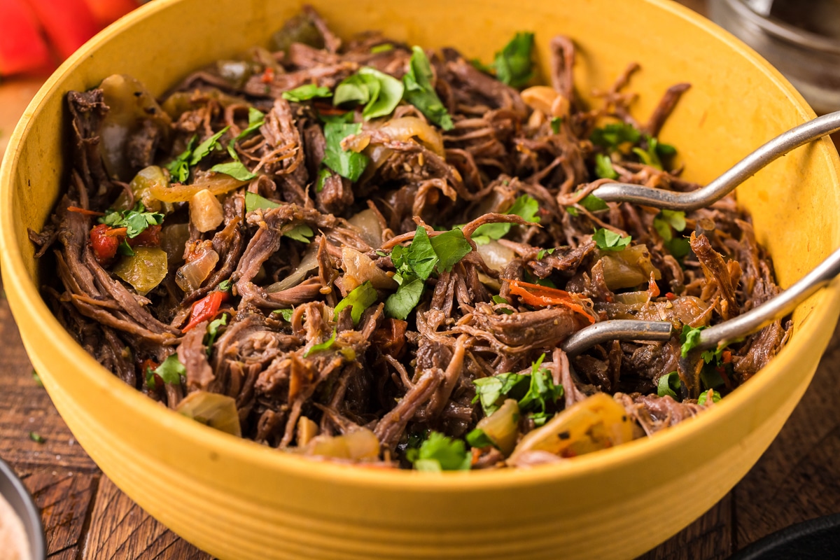 carne asada in bowl with tongs.