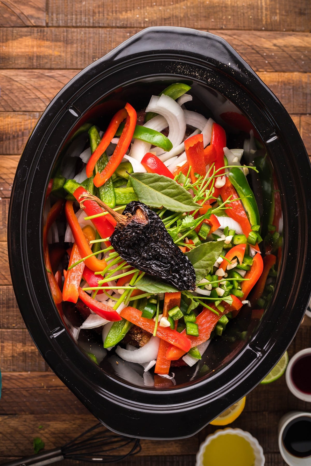 Beef, seasonings, onions and peppers in a slow cooker for carne asada.