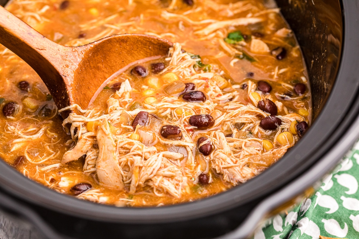 close up of chicken tortilla soup with wooden spoon in it.