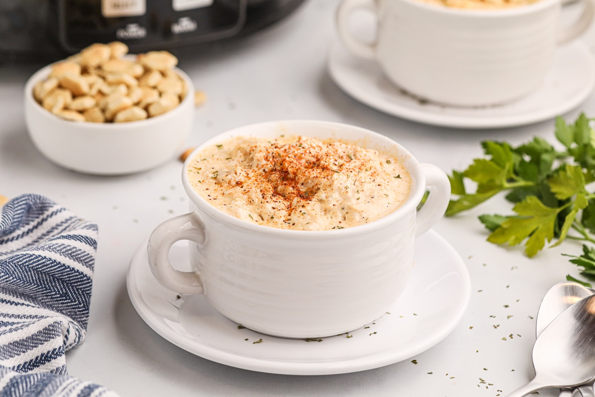 cream of crab soup in white bowl with old bay seasoning on top.