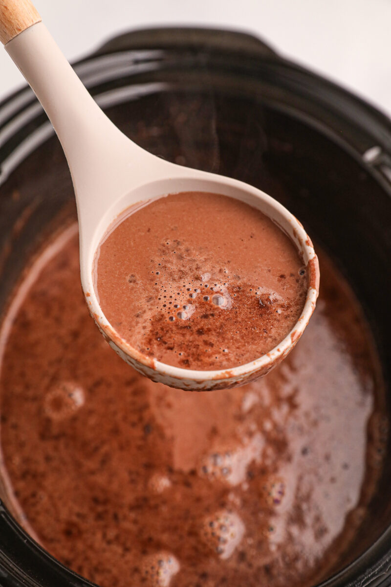 Hot chocolate on a spoon coming from crockpot.