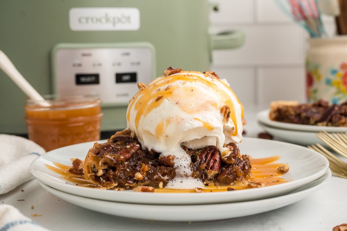 slice of pecan pie on plate with ice cream and caramel.