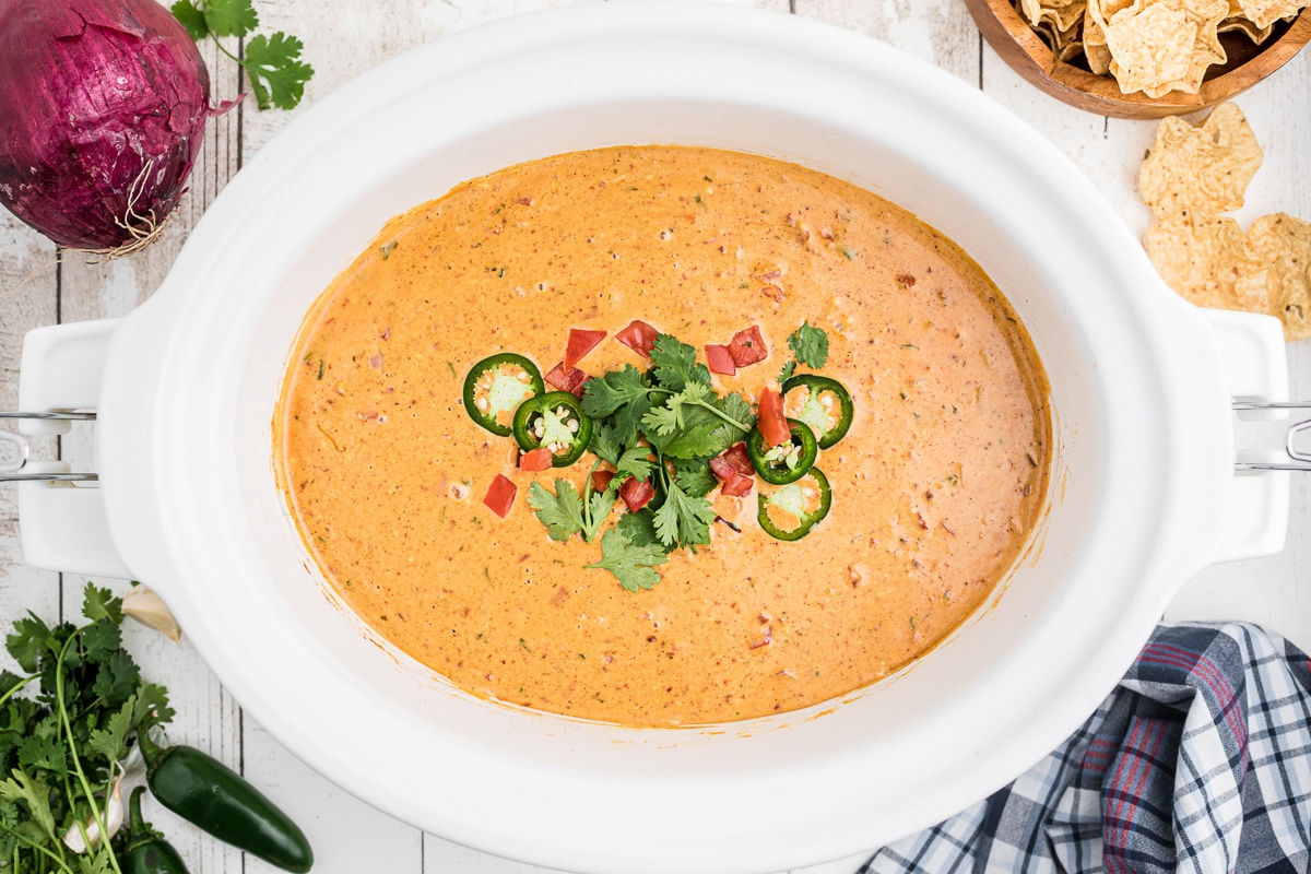 over head shot of smoked queso with cilantro, tomatoes and jalapeno on top.