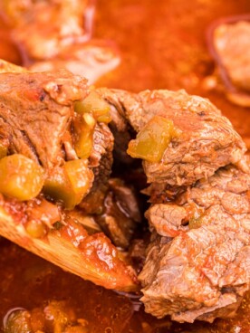 close up of steak burrito filling on a wooden spoon.