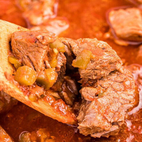 close up of steak burrito filling on a wooden spoon.