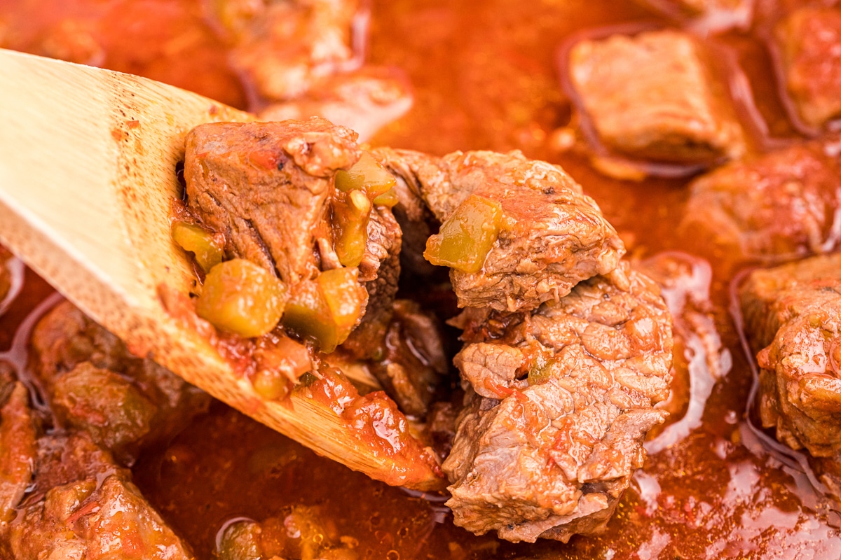 close up of steak burrito filling on a wooden spoon.