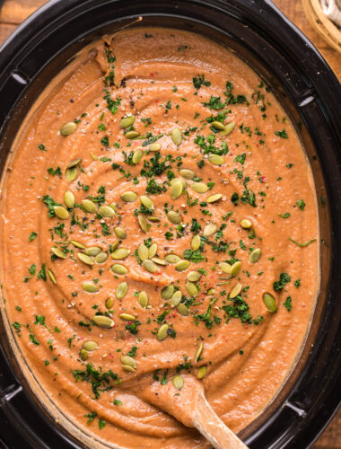 overhead shot of sweet potato soup with pumpkin seeds on top.