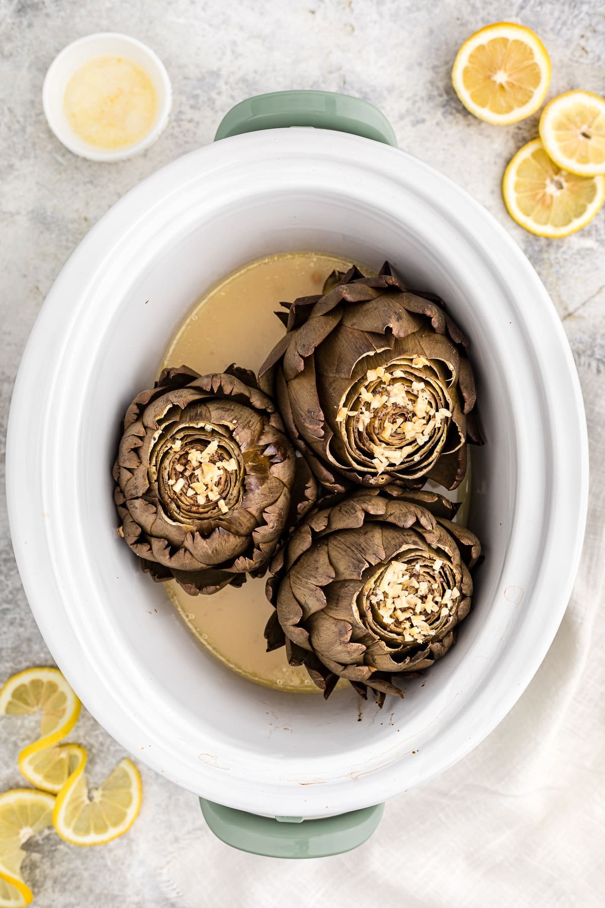 Overhead photo of cooked artichokes in a crockpot.