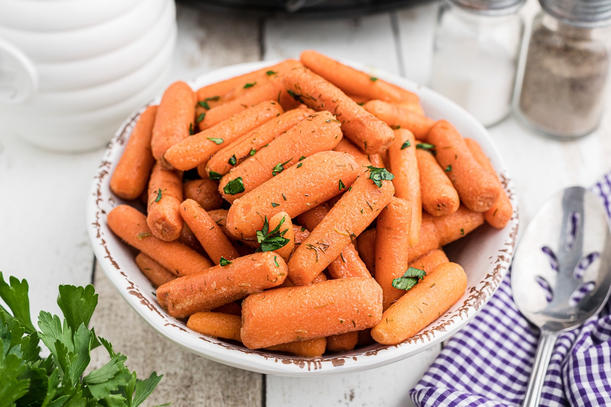 bowl of baby carrots with parsley on top.
