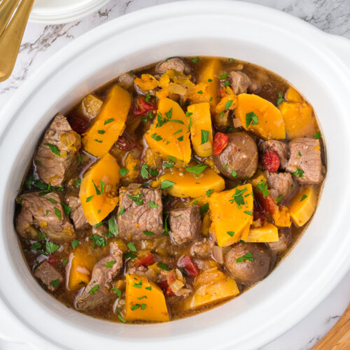 butternut beef stew in a white slow cooker.