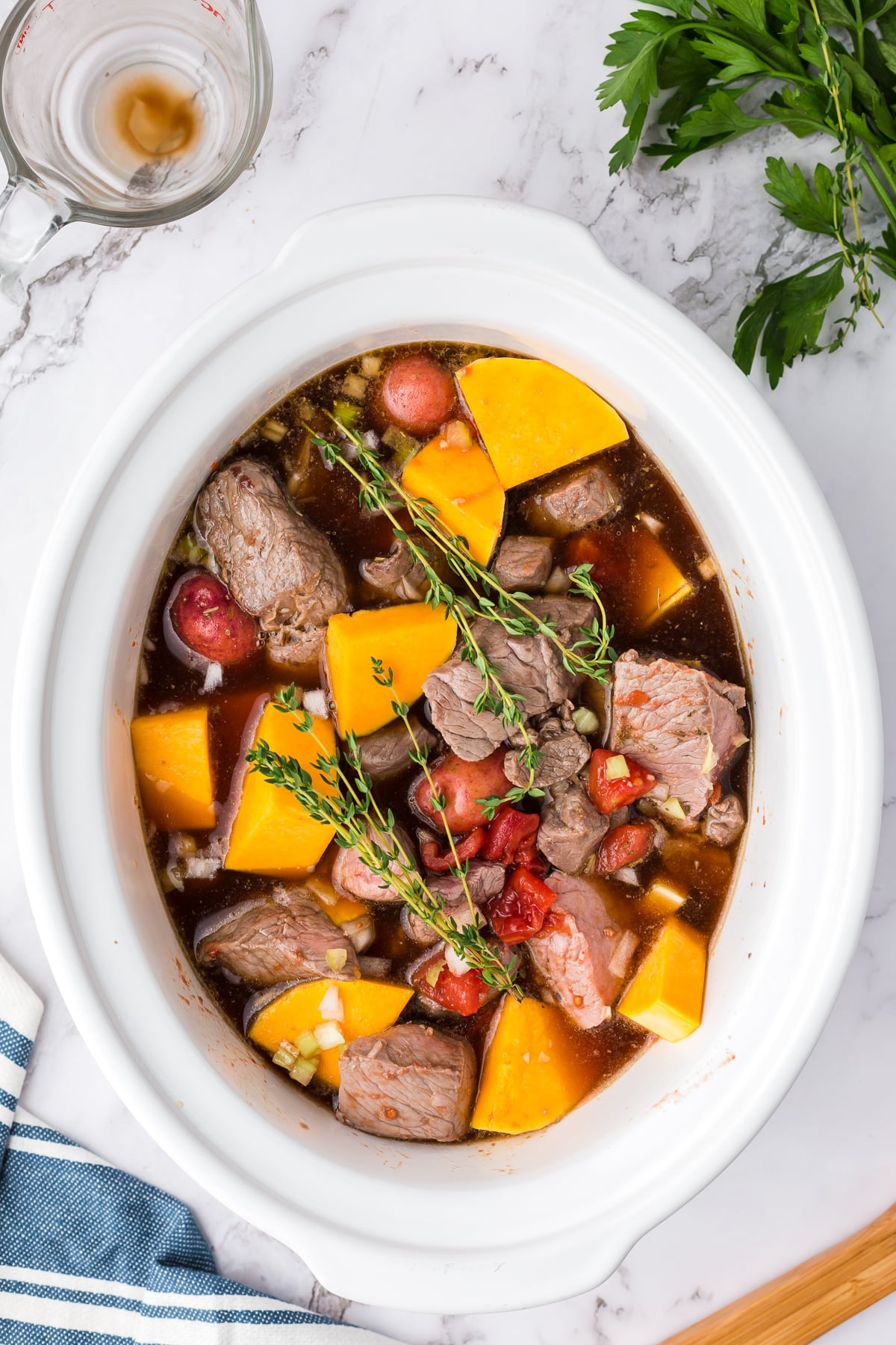butternut squash beef stew in a slow cooker with seasonings and broth.