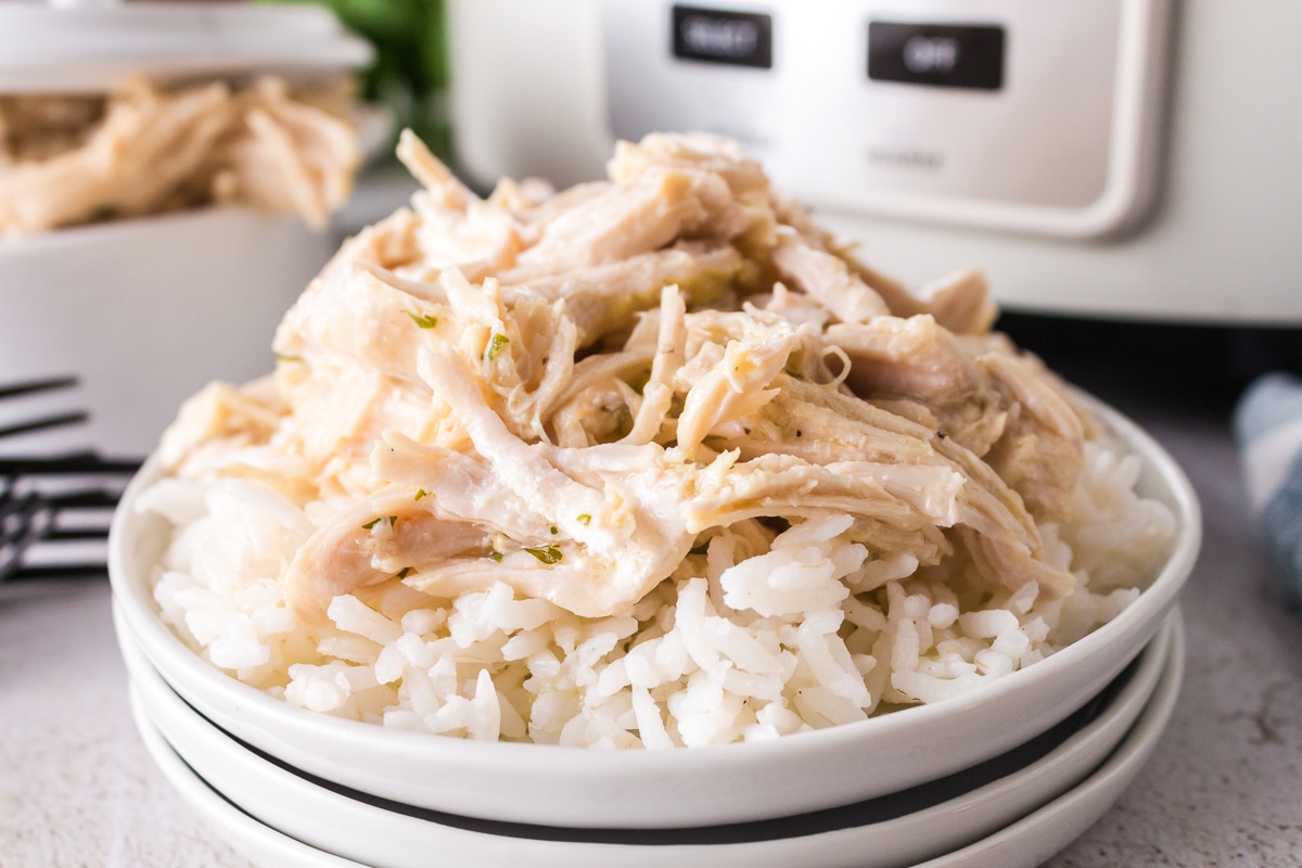 bowl of shredded caeser chicken on a bed of rice.