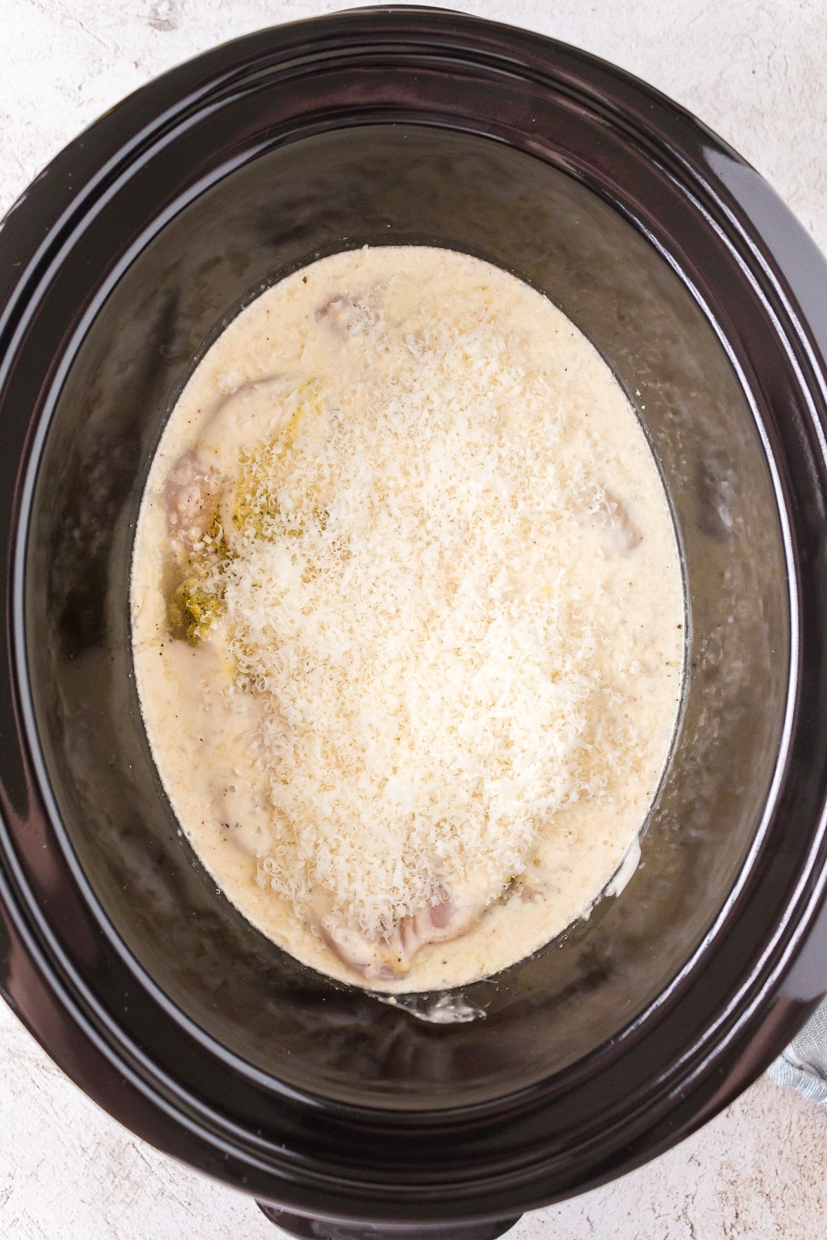 chicken in caesar dressing and parmesan in a slow cooker.