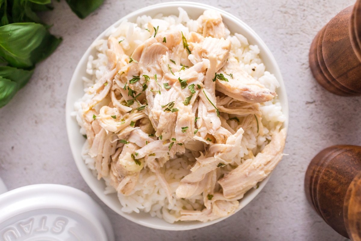 Shredded caeser chicken in a bowl with parsley on top.