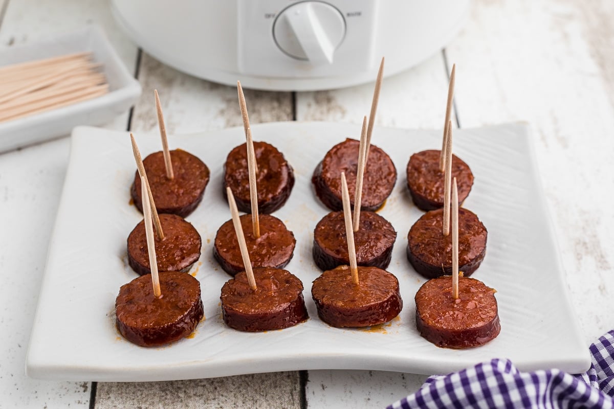 Kielbasa slices with toothpicks on a plate.