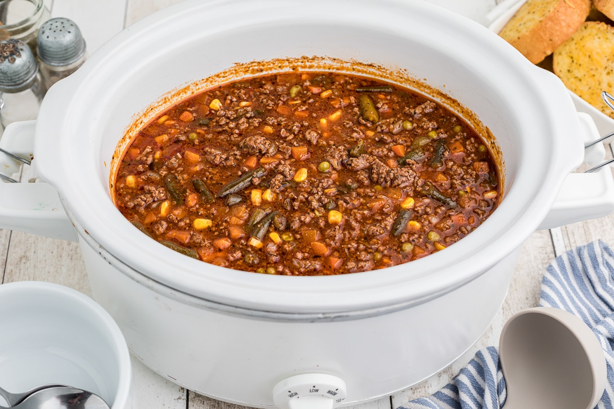 side view of hamburger soup in a white slow cooker.