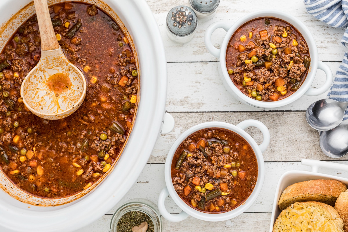 hamburger soup in slow cooker and two bowls.