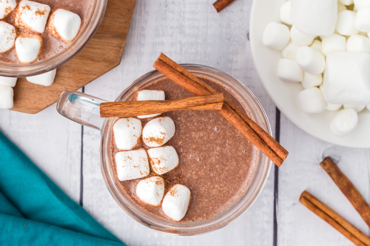 Mexican hot chocolate in a mug with cinnamon sticks on top.