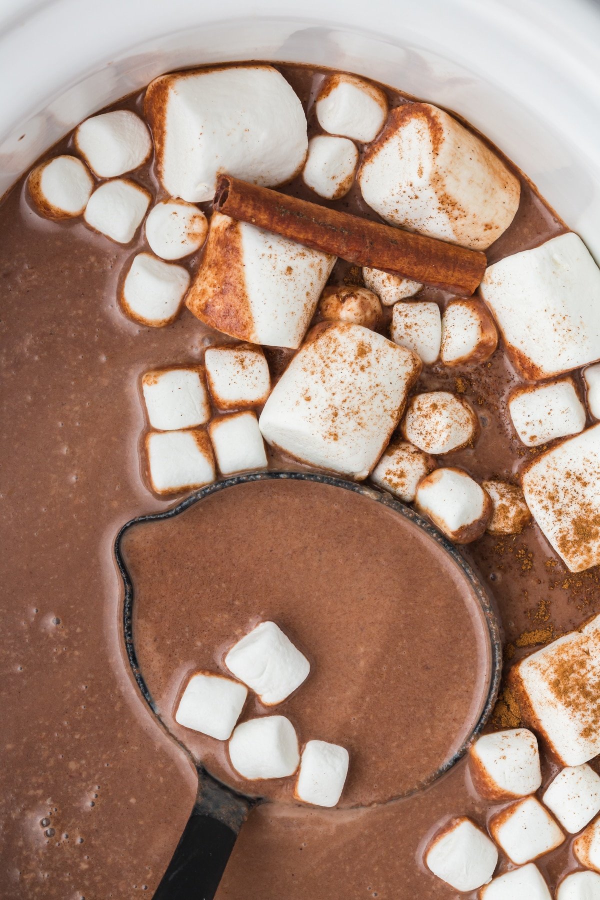 Spoon of mexican hot chocolate coming from slow cooker.