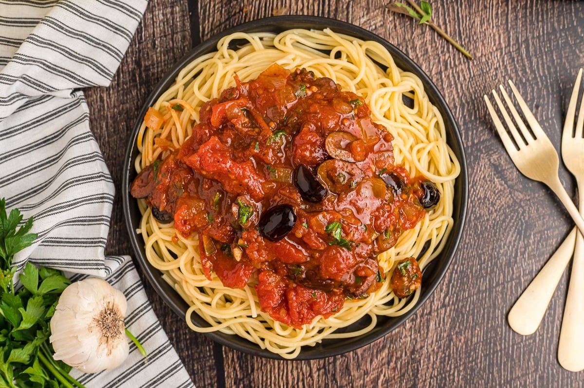 plate of spaghetti with puttanesca sauce on top.