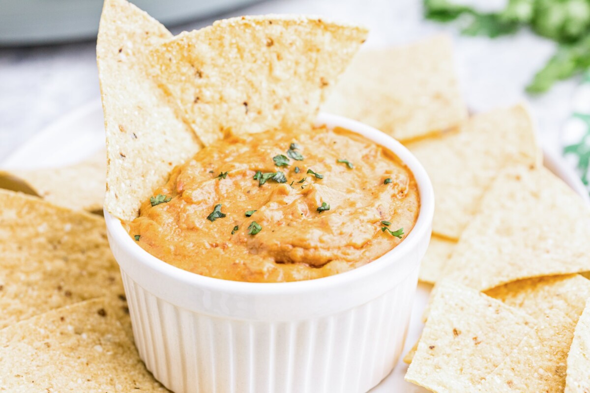 bean dip in a bowl with chips sticking in it.