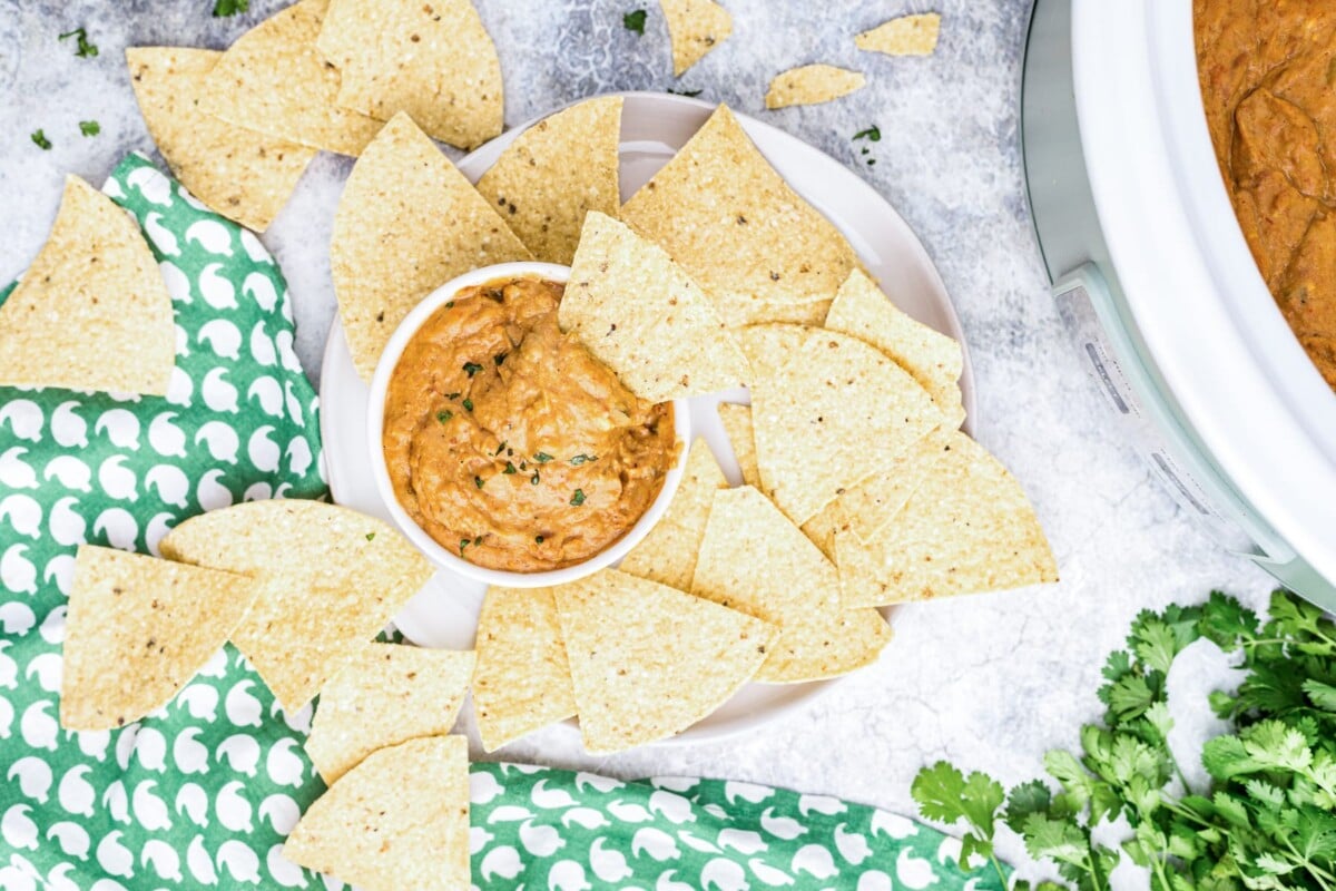  bean dip in a bowl with chips around it.