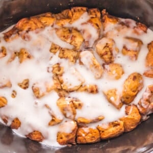 CInnamon roll casserole with icing in a slow cooker.